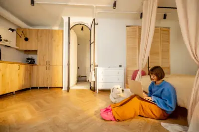 woman-works-on-laptop-at-modern-studio-apartment-2025-03-18-13-21-14-utc Apartemen Akses Dekat Kota dan Kawasan Hijau